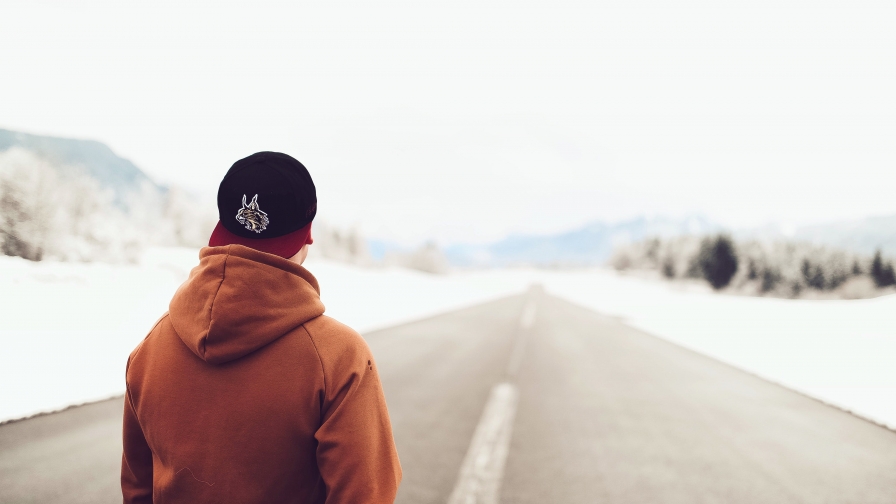 Person in Brown Hoodie Standing on Asphalt Road